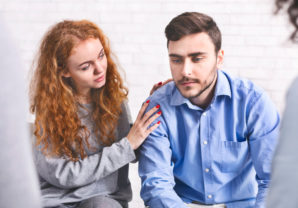 Woman Comforting Depressed Man At Rehab Group Meeting