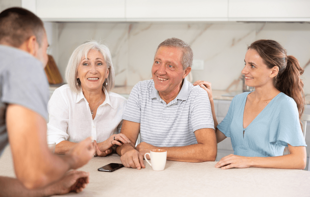 Happy elderly couple at a table with adult children